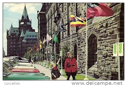 ROYAL CANADIAN MOUNTED POLICE CORPORAL AND VISITOR ADMIRE FLAGS OF MANY COUNTRIES ON PARLIAMENT HILL. - Ottawa