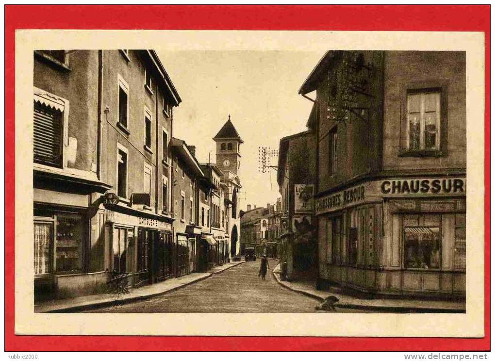 MONTLUEL GRANDE RUE ET EGLISE SAINT ETIENNE CHAUSSEUR HORLOGERIE DROGUERIE CARTE EN TRES BON ETAT - Montluel