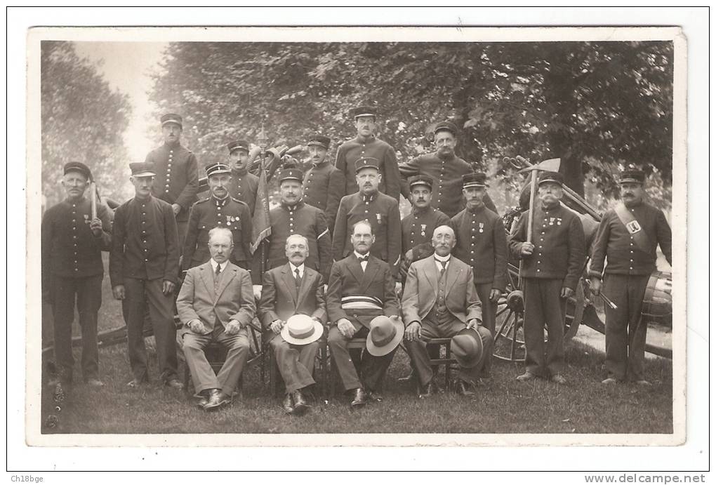 Carte Photo : Non Située : 4 Civils Assis Devant Des Hommes En Uniformes ( Sapeurs ?) Certains Portant Une Hache - Autres & Non Classés