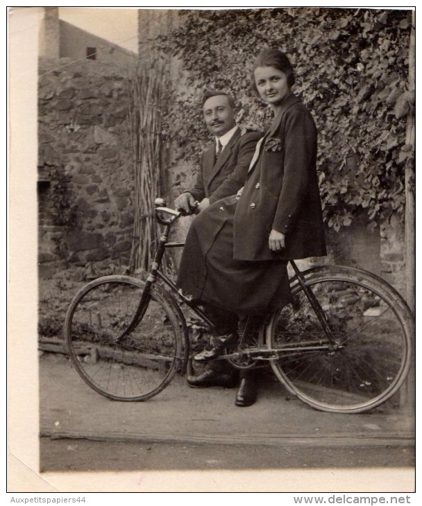 Photo Originale Vélo - Couple Avec Bicyclette - Madame Sur Le Vélo - Monsieur Tient Le Guidon - Fiers - Mode - Cyclisme