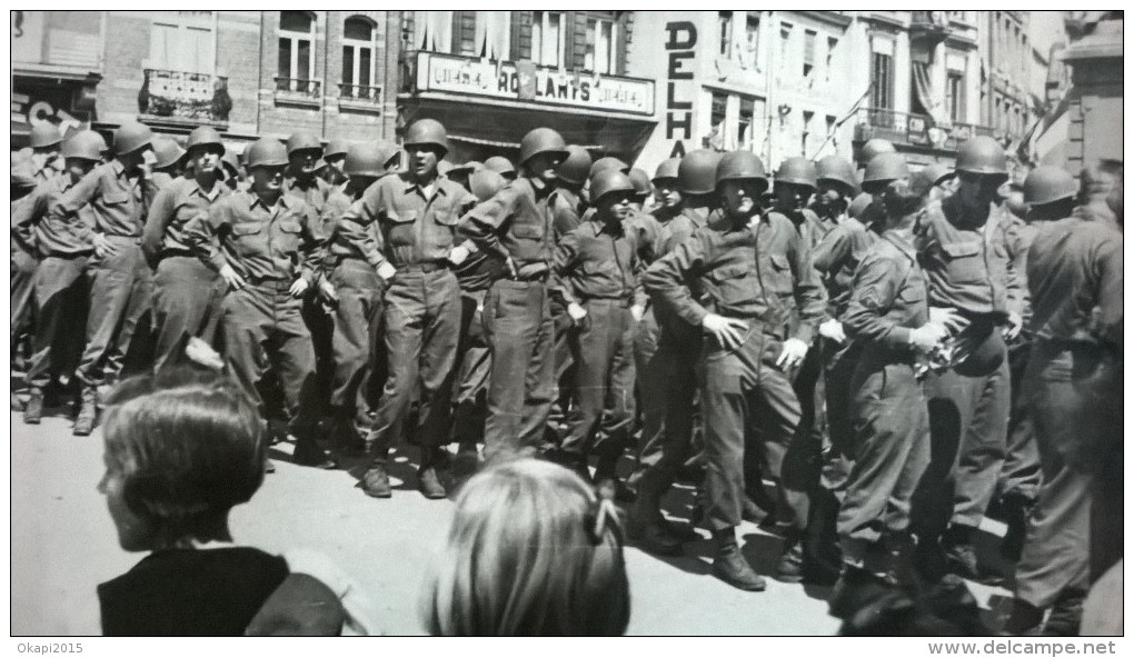 Une Photo De Militaires , En File, En Ville, Enseigne " Ro?lants". Cachet Au Dos: Un Nom( De Militaire?) , Ville Heusy. - Guerra, Militari