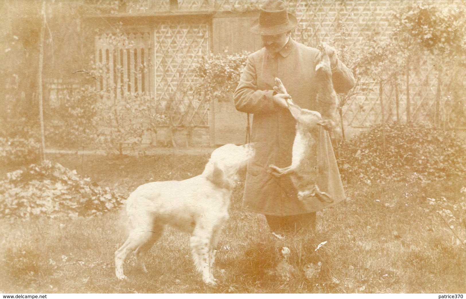 Carte PHoto D'un Chasseur Qui Montre à Son Chien De Chasse Le Gibier Lapins Maison Derrière à Identifier - Caccia