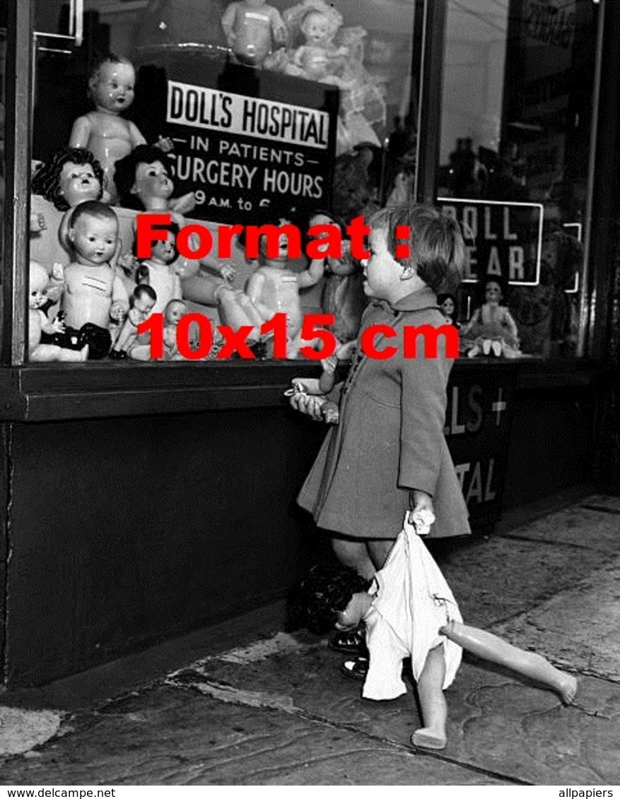 Reproduction D'une Photographie Ancienne D'une Fillette Avec Sa Poupée Devant Un Magasin De Poupées En 1957 - Autres & Non Classés