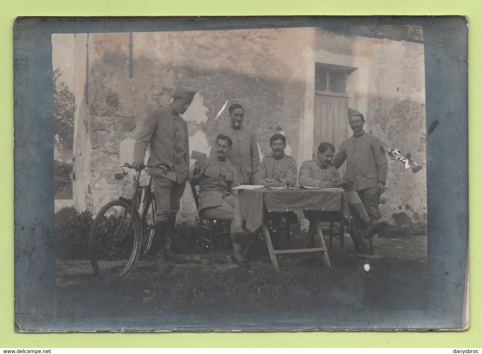 Photographie - Carte-Photo - 3 Militaires Assis à Une Table, 3 Autres Debouts Dont Un Tient Un Vélo - 1914-18