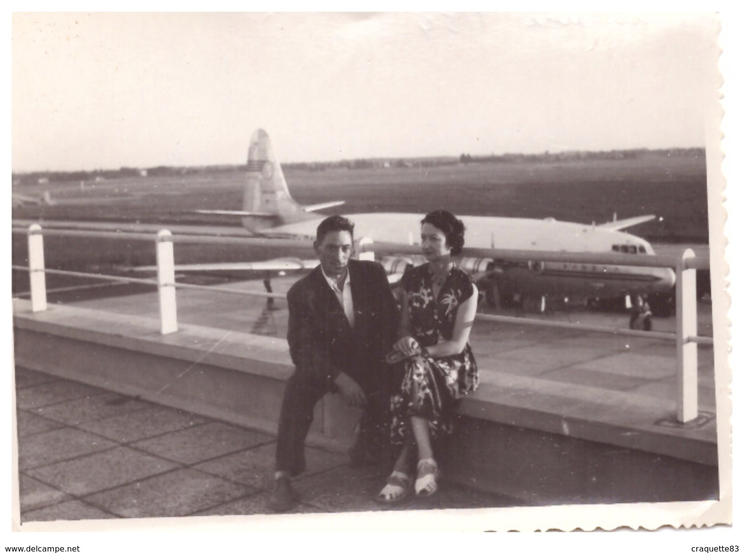 TOULOUSE  LE 9/1954   COUPLE ASSIS SUR LA TERRASSE DE L'AEROPORT   EN CONTREBAS UN AVION DE LIGNE - Aviation