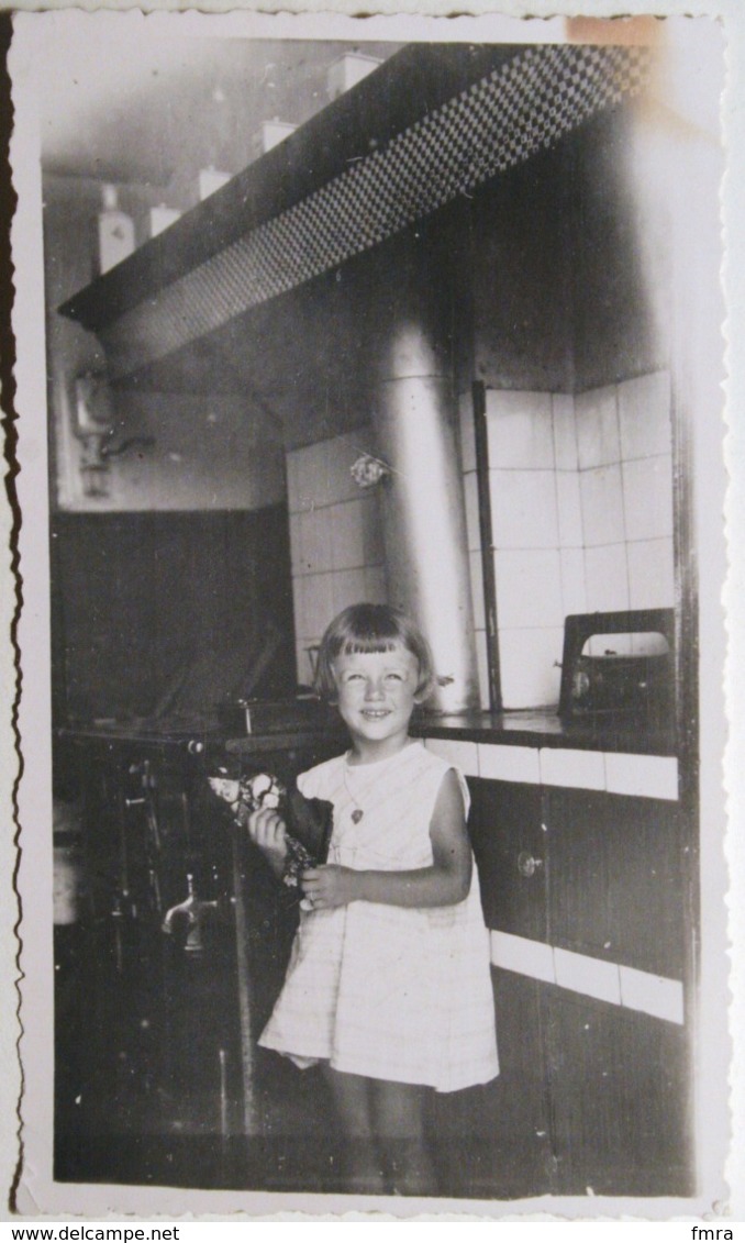 Photo 11 X 6,5 Cm - Petite Fille Avec Sa Poupée Alsacienne En Cuisine - "Souvenir De Istres - Juillet 1934" Au Dos /BR17 - Autres & Non Classés