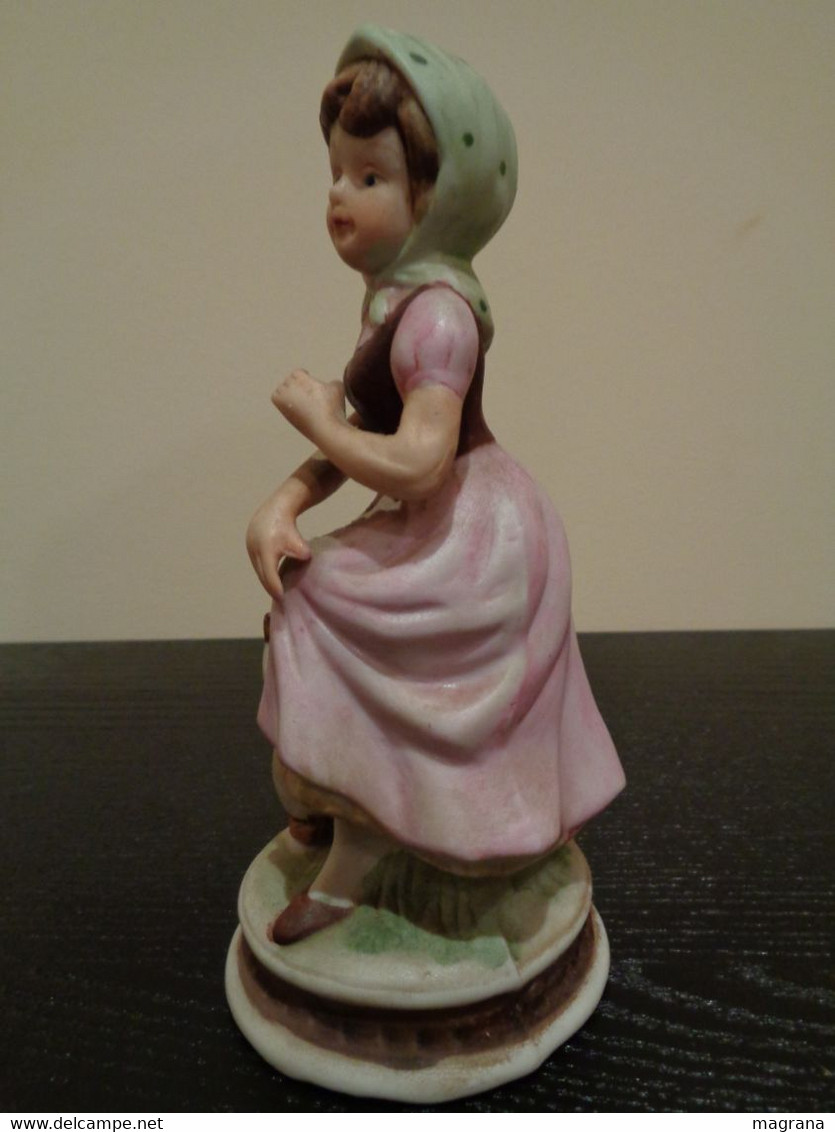 Figura de porcelana de una niña con vestido rosa y un pato.