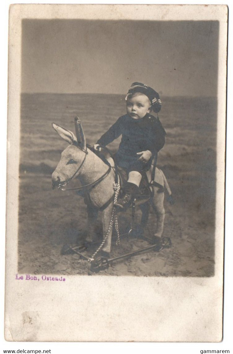 OSTENDE - CARTE PHOTO - LE BON - Surréalisme - Bébé Cavalier Sur Ane A Roulettes Sur La Plage - Cpa Belgique - Oostende