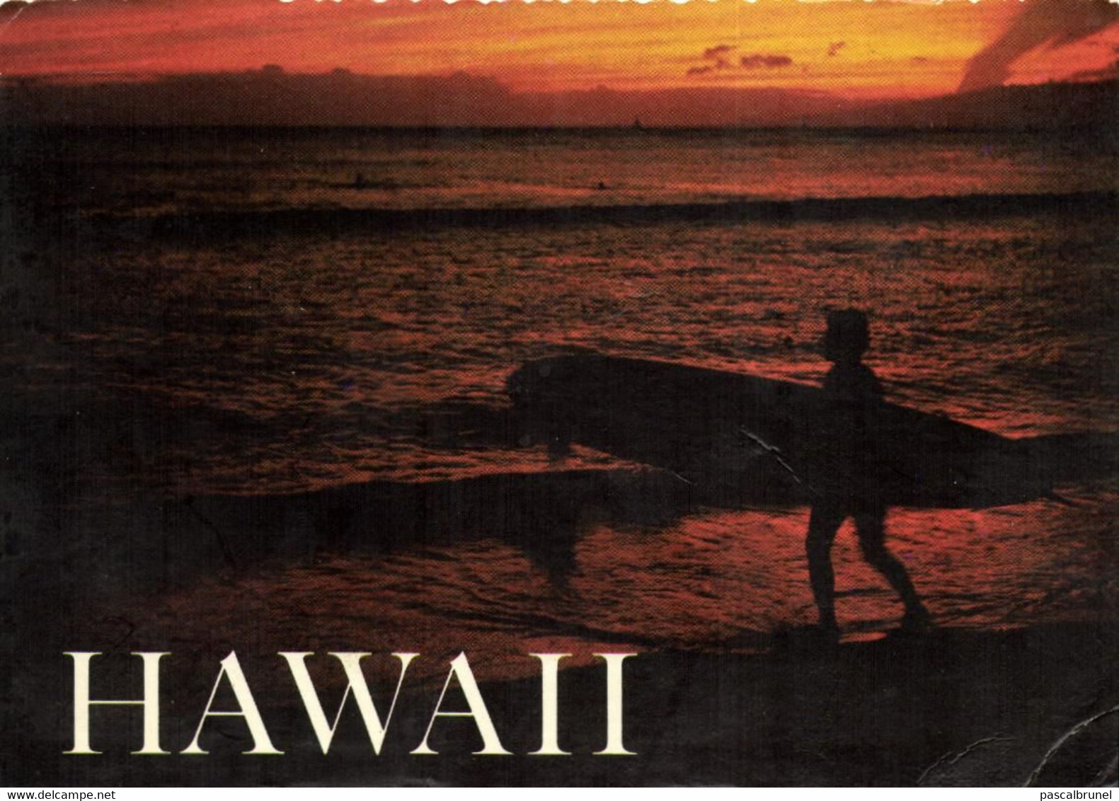 A SURFER SILENTLY WATCHES THE REFLECTION OF A GOLDEN HAWAIIAN SUNSET ACROSS THE QUIET SURF OF THE PACIFIC - Hawaï