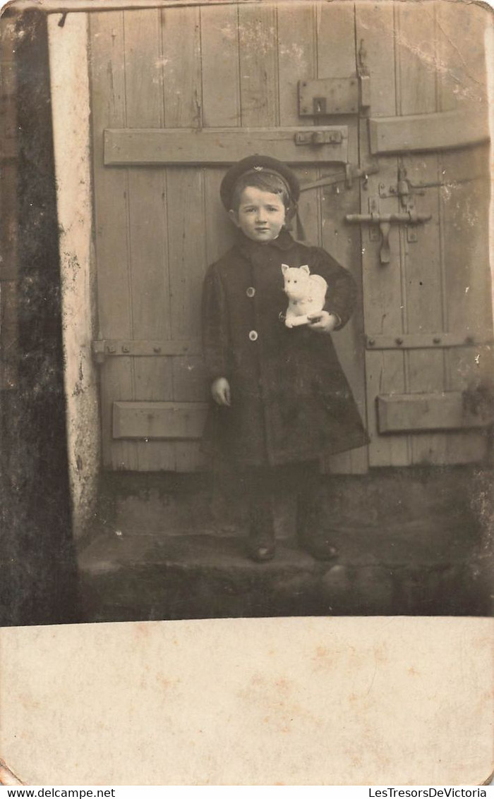 CPA Photo D'une Petite Fille Devant Une Grande Porte Avec Une Peluche Chat Dans Les Bras - Photographie