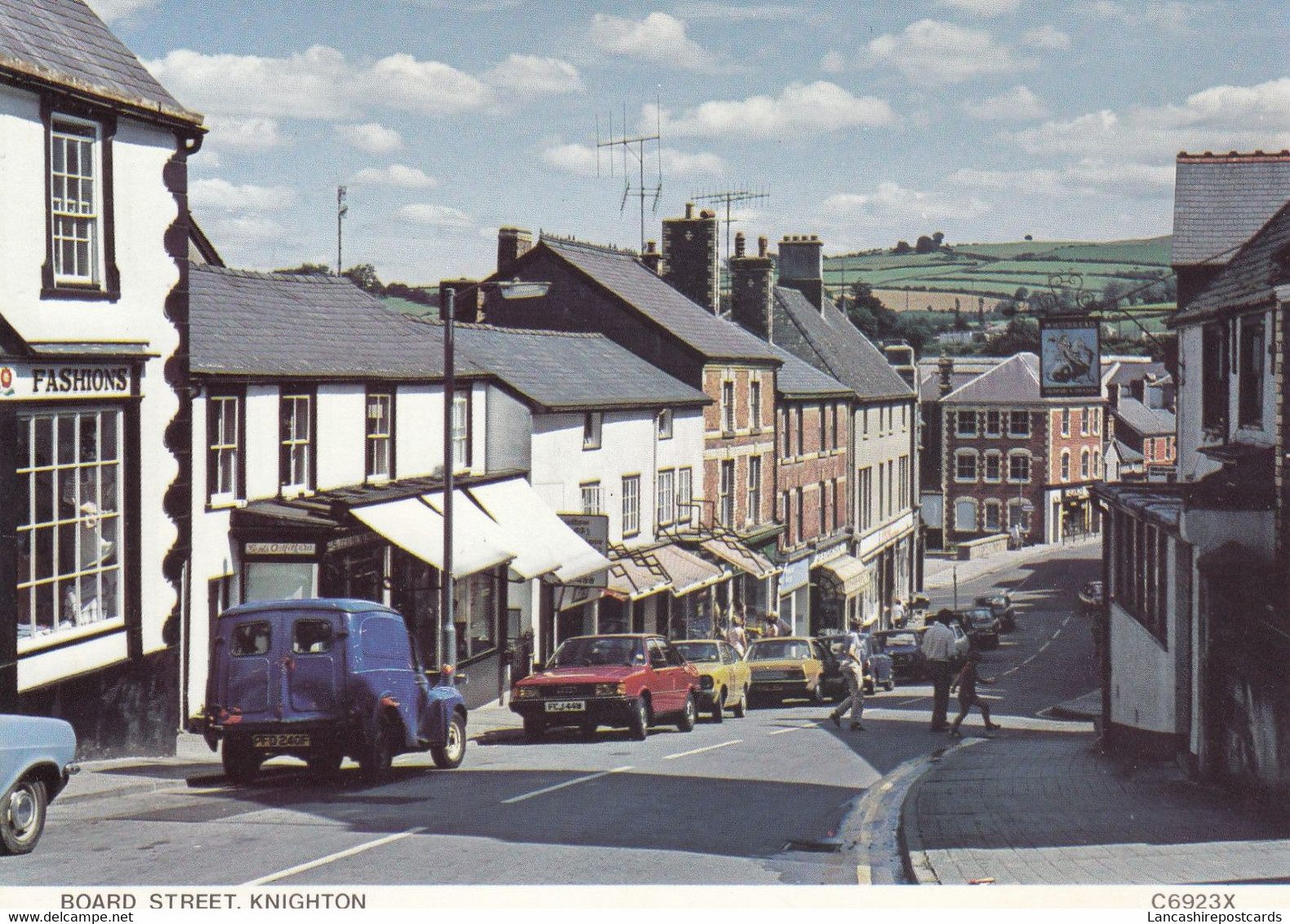 Postcard Broad Street Knighton Shops Pub People [ Old Cars Blue Morris 1000 Van & Red Audi ]  My Ref B26090 - Radnorshire