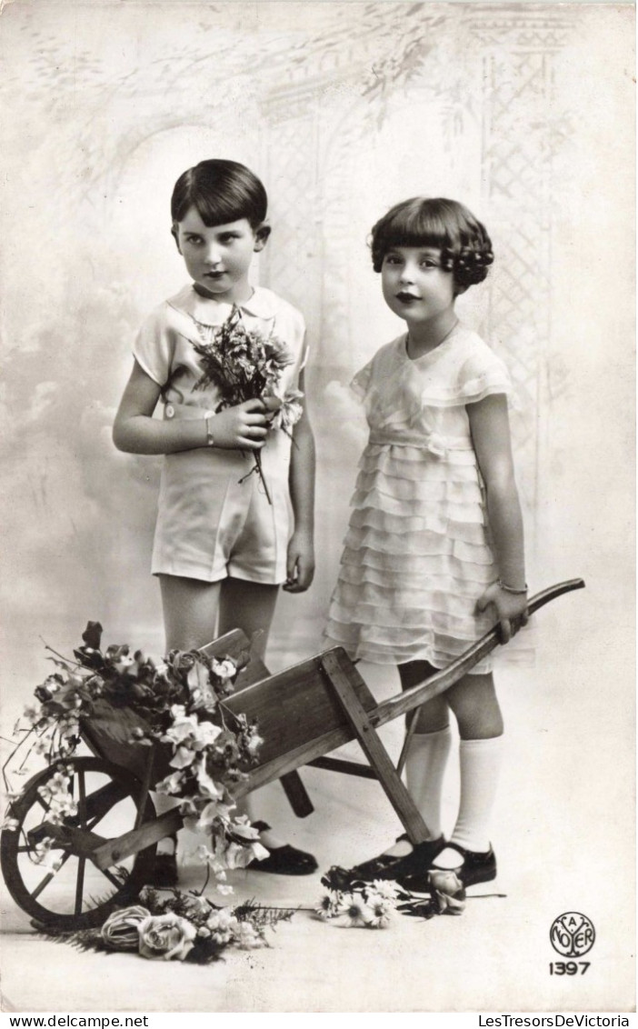 Enfants - Un Frère Et Une Sœur Posant Près D'une Brouette De Fleurs -  Carte Postale Ancienne - Gruppi Di Bambini & Famiglie