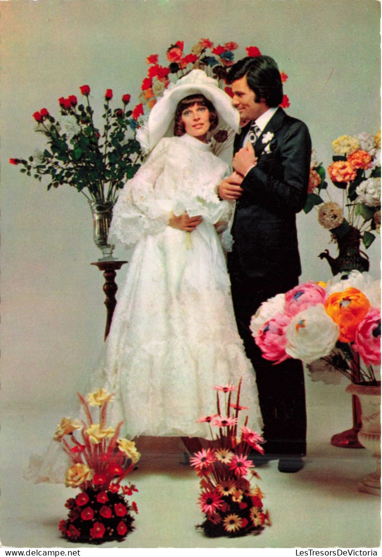 NOCES - L'époux Et La Mariée - Des Mariés Entourés De Fleurs - Murs Blancs - Colorisé - Carte Postale - Marriages