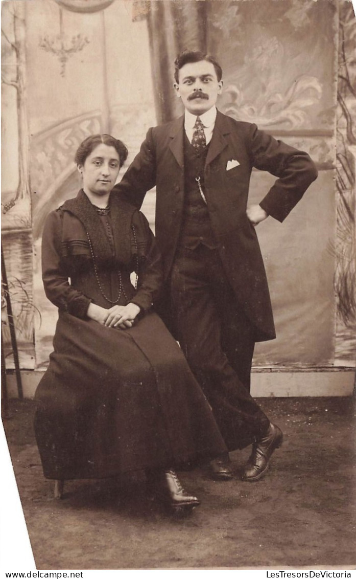 COUPLE - Un Couple Habillé En Noir - Femme Assise Sur Une Chaise - Carte Postale Ancienne - Koppels