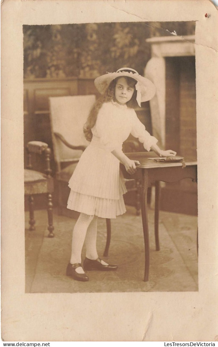 ENFANT - Une Petite Fille Avec Un Chapeau Se Tenant à Côté De La Table - Carte Postale Ancienne - Portraits