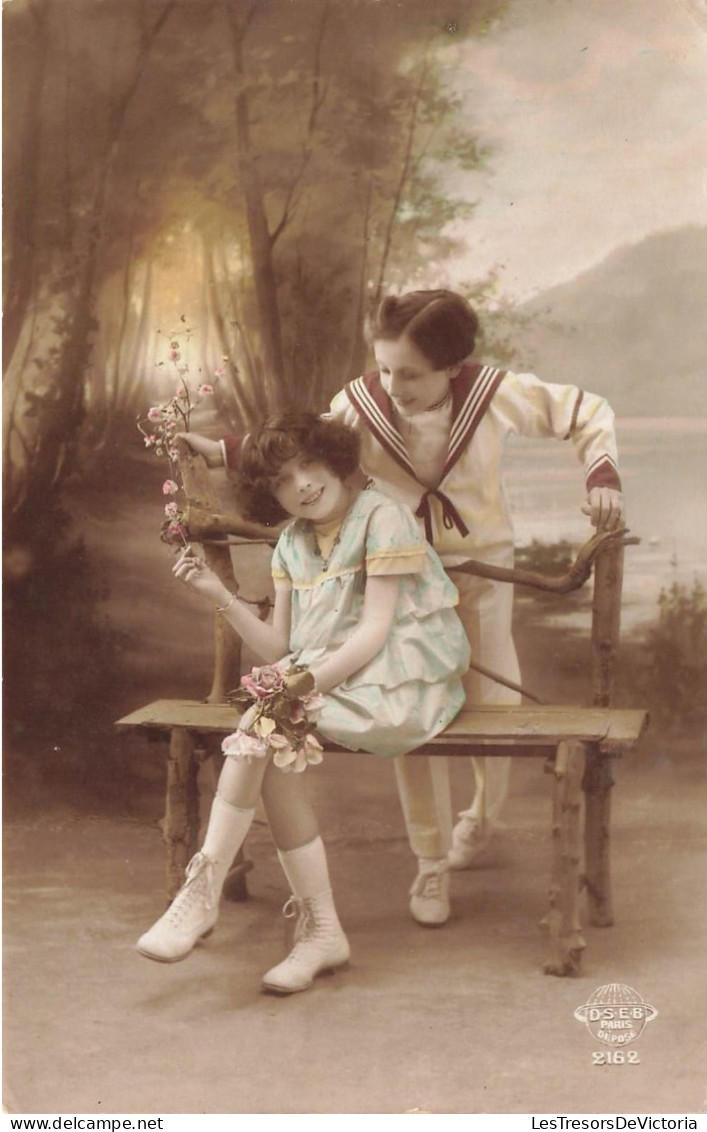 FANTAISIES - Deux Enfants - Une Jeune Fille Tenant Un Bouquet De Fleur Assise - Un Jeune Garçon - Carte Postale Ancienne - Met Mechanische Systemen