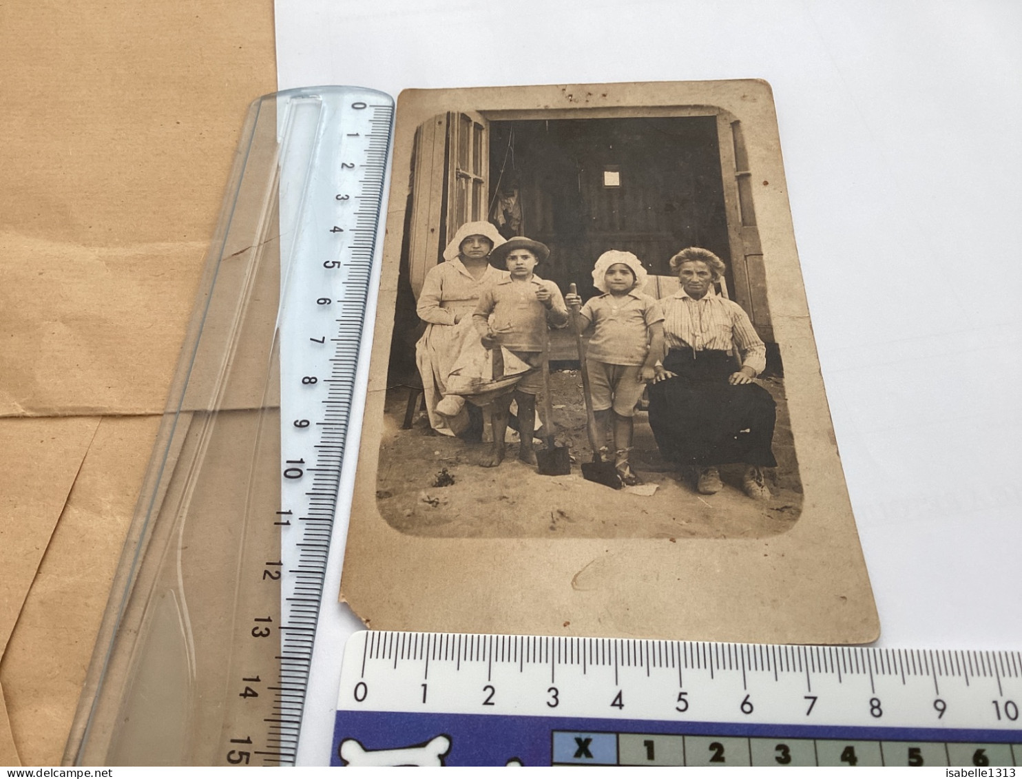 Photo Snapshot 1930 Photo, Carte Femme, Assise Devant La Maison Avec Chapeau, Garçon, Fille, Pieds Nus Avec Des Pelles D - Oggetti