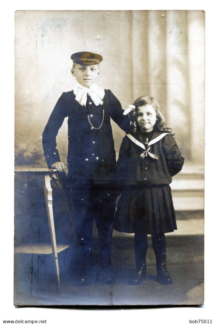 Carte Photo D'un Jeune Garcon élégant Avec Une Petite Fille élégante Posant Dans Un Studio Photo En 1913 - Personnes Anonymes