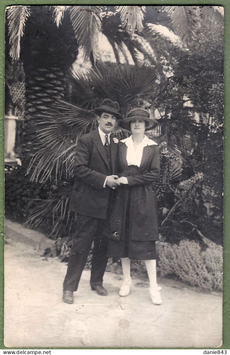 CARTE PHOTO -  COUPLE ÉLÉGANT DANS UN DÉCORS VÉGÉTAL TROPICAL , MODE, CHAPEAUX - - Mode