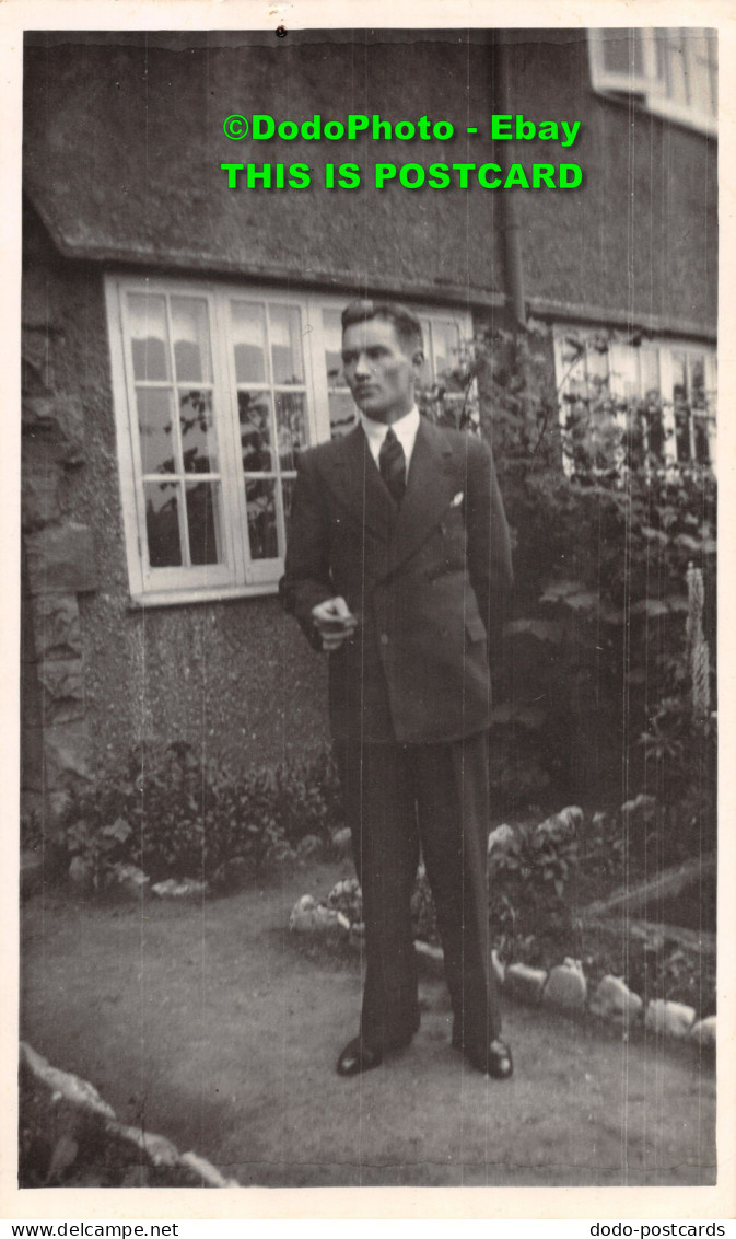 R396504 A Man In A Suit Is Standing By The House. Postcard - Monde