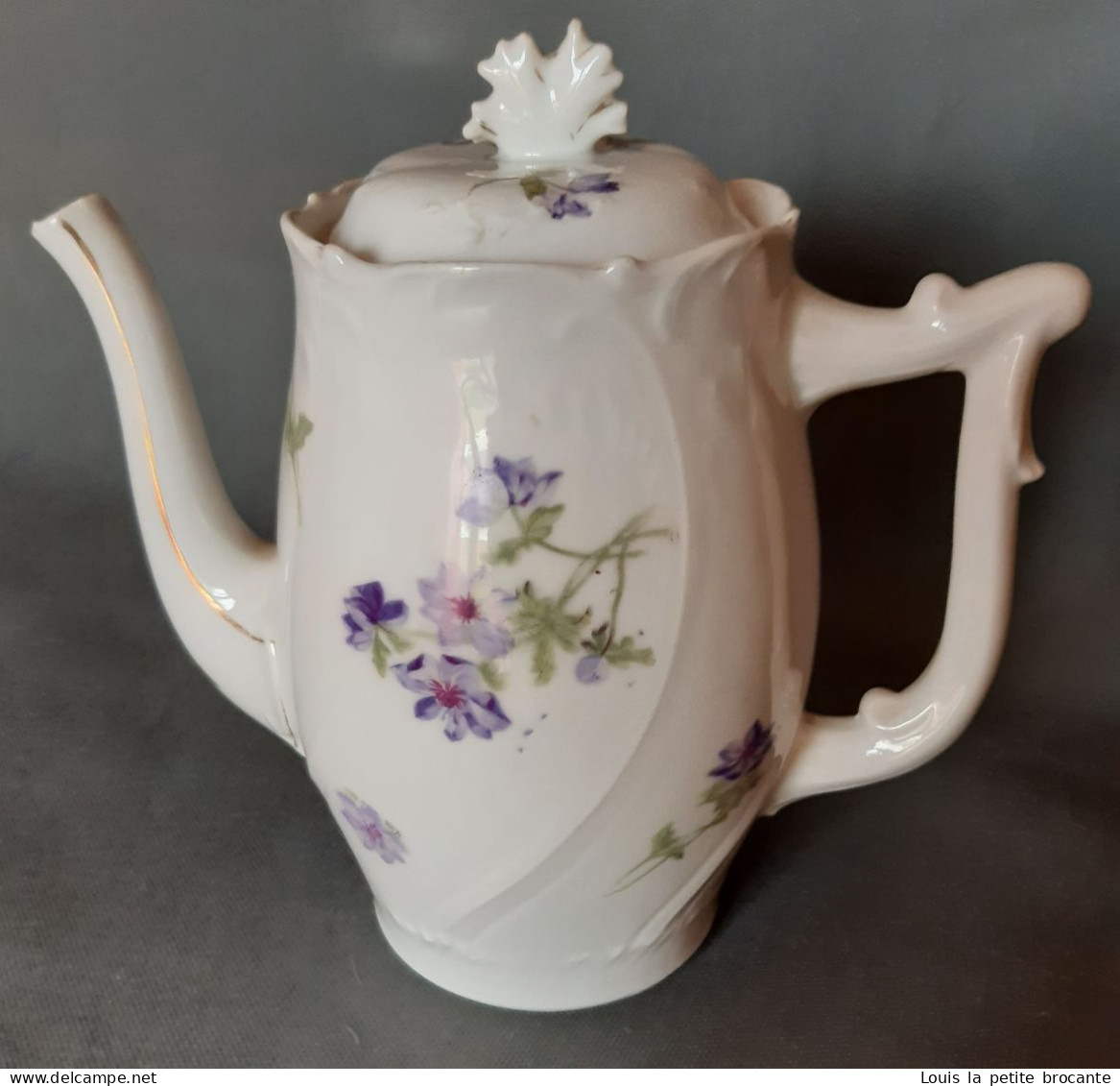 Cafetière En Porcelaine, Blanche Motif Floral Violet. Un Casse Sur Le Bec Verseur. - Autres & Non Classés