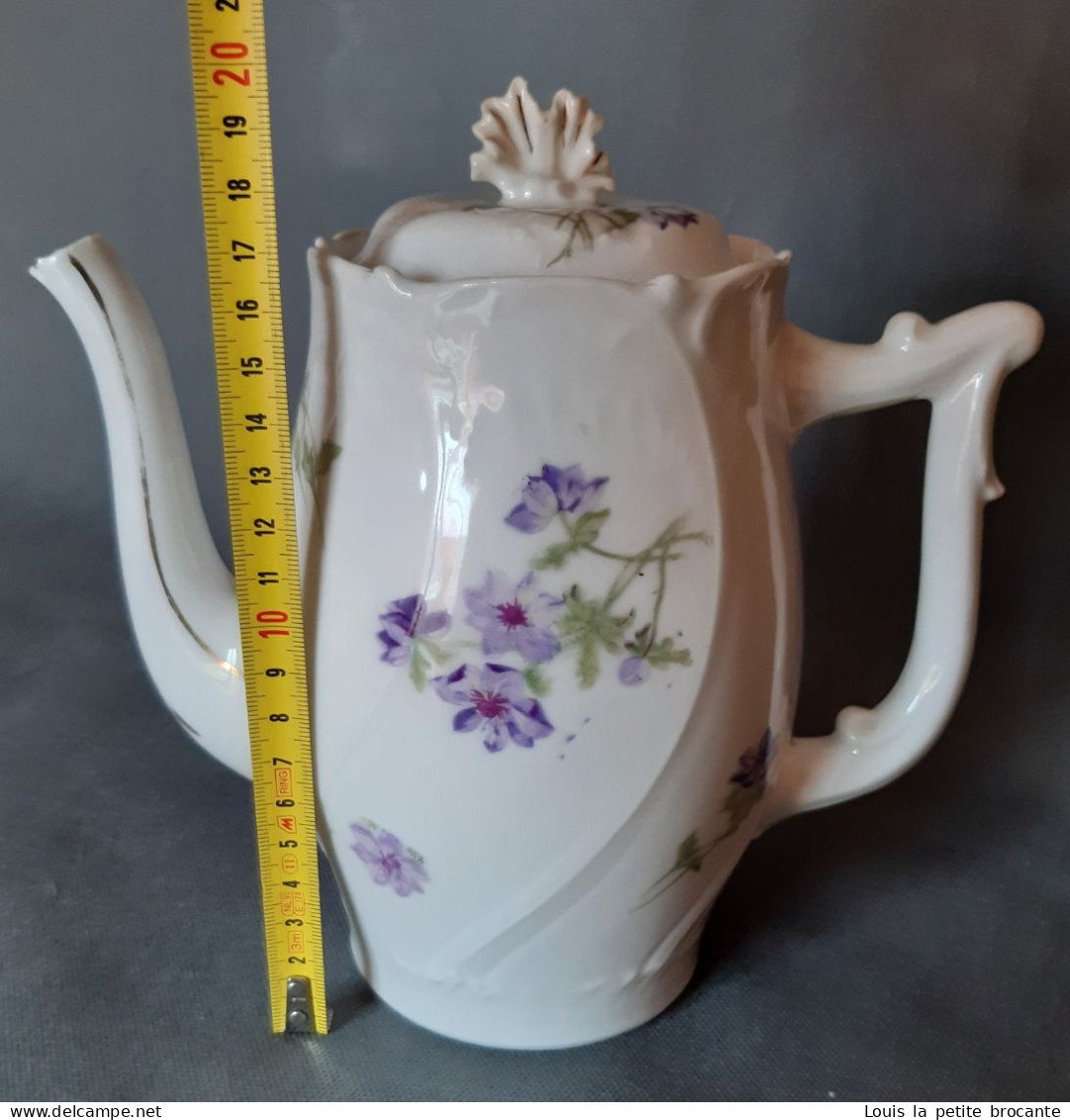 Cafetière en porcelaine, blanche motif floral violet. Un casse sur le bec verseur.