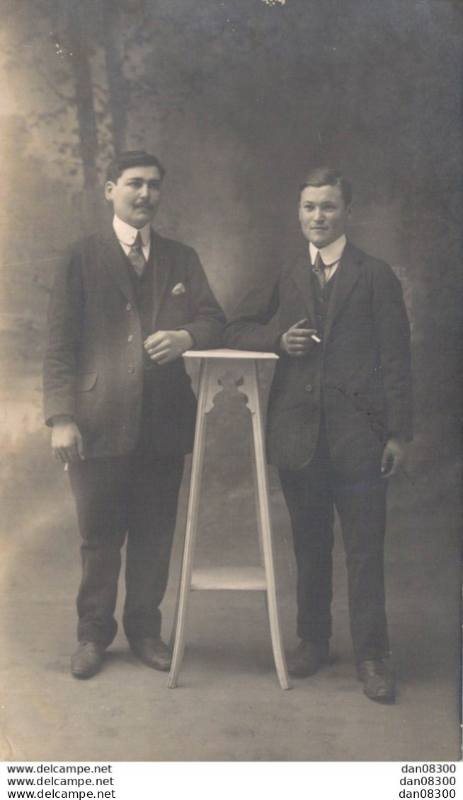 CARTE PHOTO NON IDENTIFIEE REPRESENTANT DEUX HOMMES TENANT LA POSE DANS UN STUDIO PHOTO - Te Identificeren