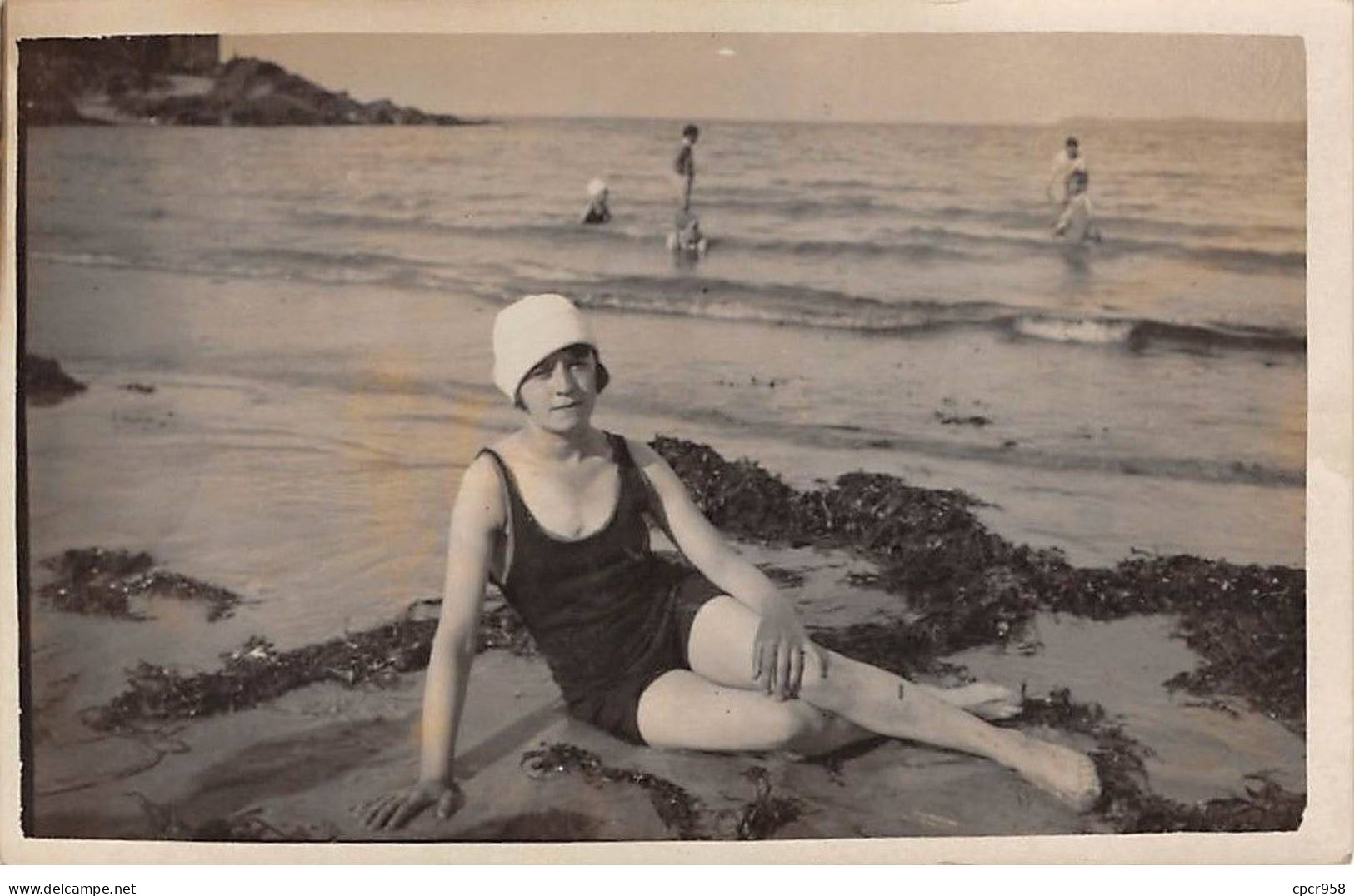 Photographie - N°91006 - Femme En Tenue De Bain Assise Sur Une Plage Entourée D'algues, Au Bord De L'eau - Fotografie
