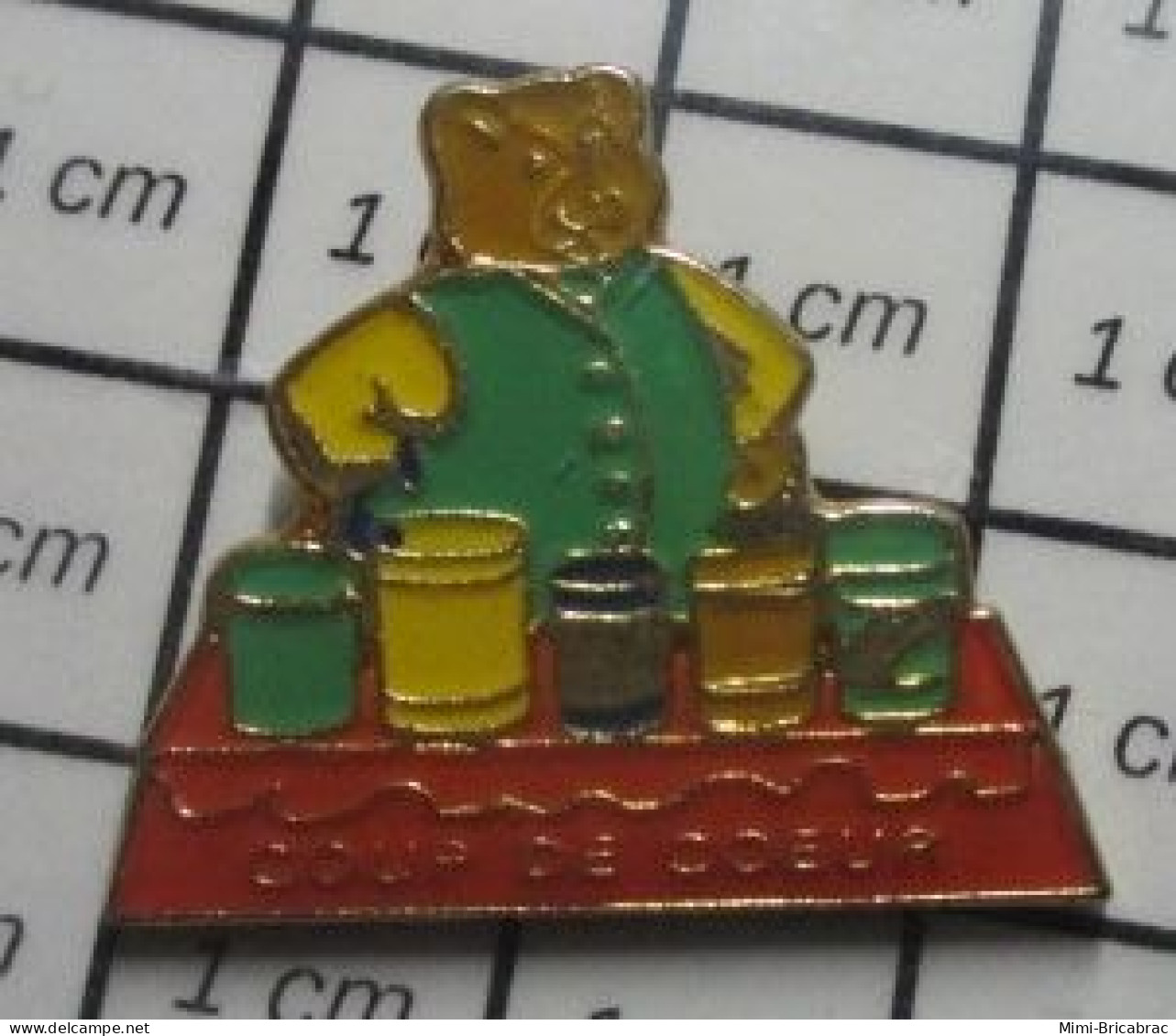 3617 Pin's Pins : Rare Et Belle Qualité : MARQUES / OURS BRUN EN GILET VERT DEVANT 5 BOITES COUP DE COEUR - Markennamen