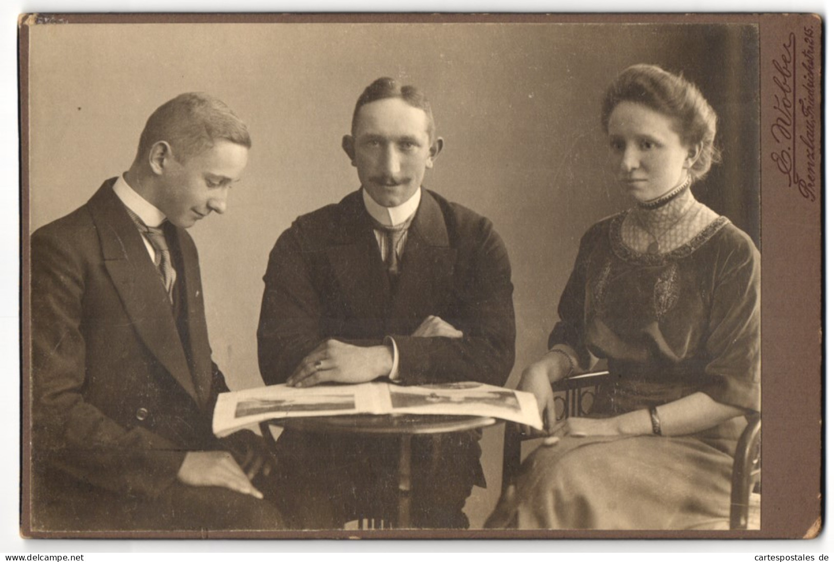 Fotografie E. Wobber, Prenzlau, Friedrichstr. 215, Junge Frau Im Kleid Und Zwei Herren Mit Zeitung Am Tisch  - Personas Anónimos