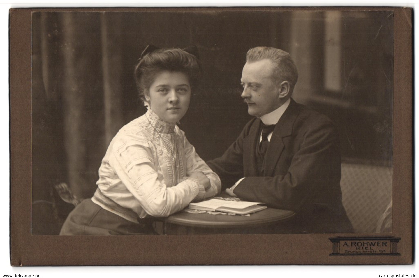 Fotografie A. Rohwer, Kiel, Brunswikerstr. 15 A, Bürgerliches Paar Mit Buch Am Tisch  - Anonyme Personen