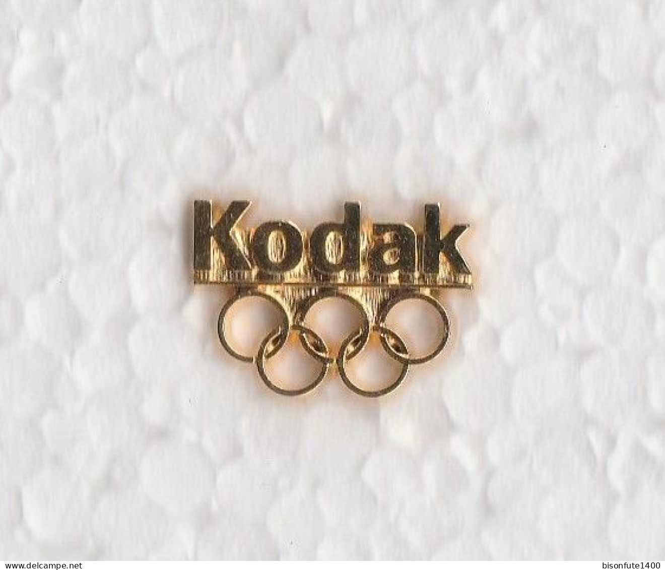 1 Pin's Avec Publicité KODAK Et Anneaux Olympiques - En Métal Doré Et 1 Attache. - Giochi Olimpici