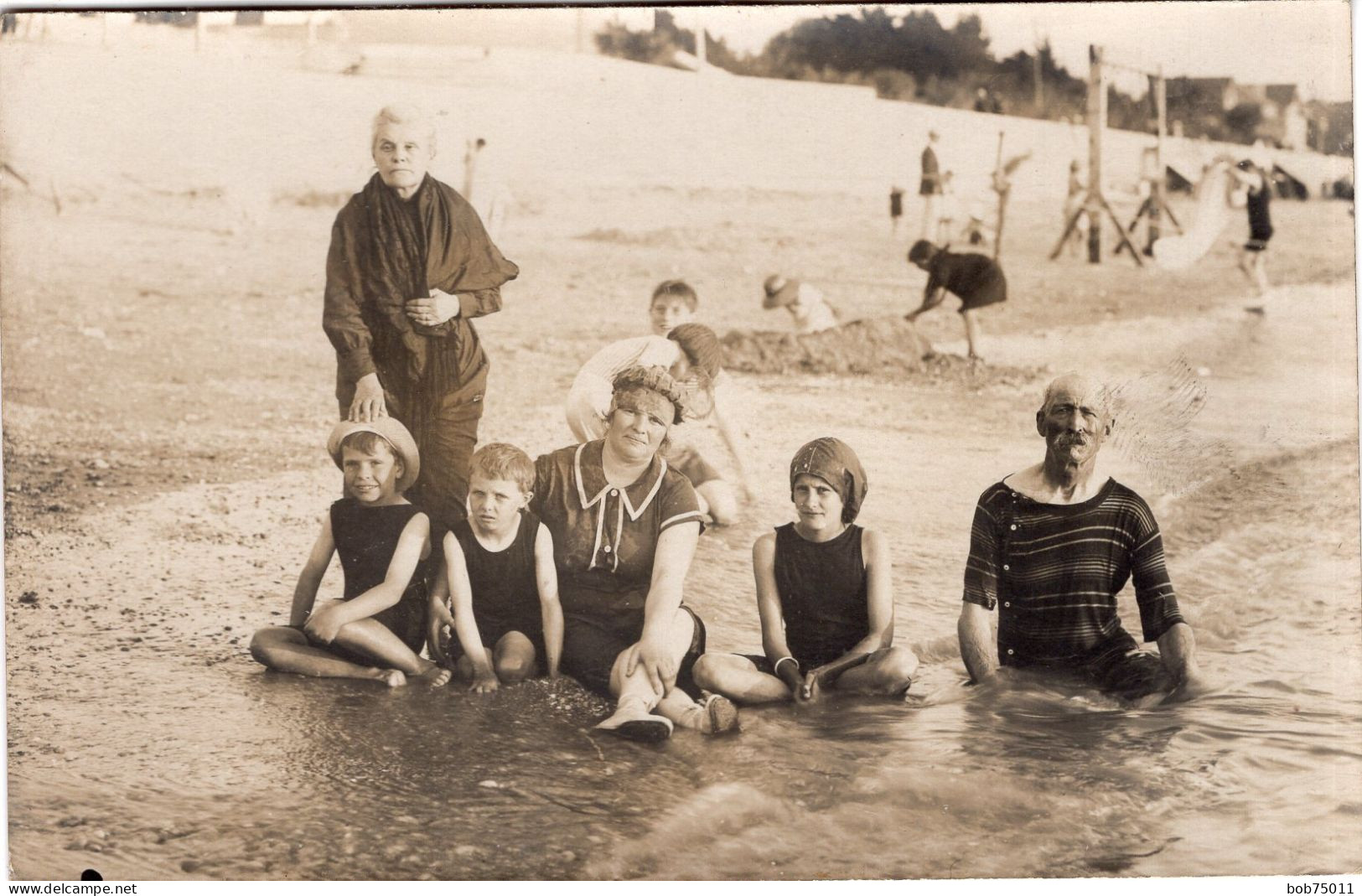 Carte Photo D'une Famille En Maillot De Bain Assise Sur Une Plage Animé Vers 1920 - Personnes Anonymes