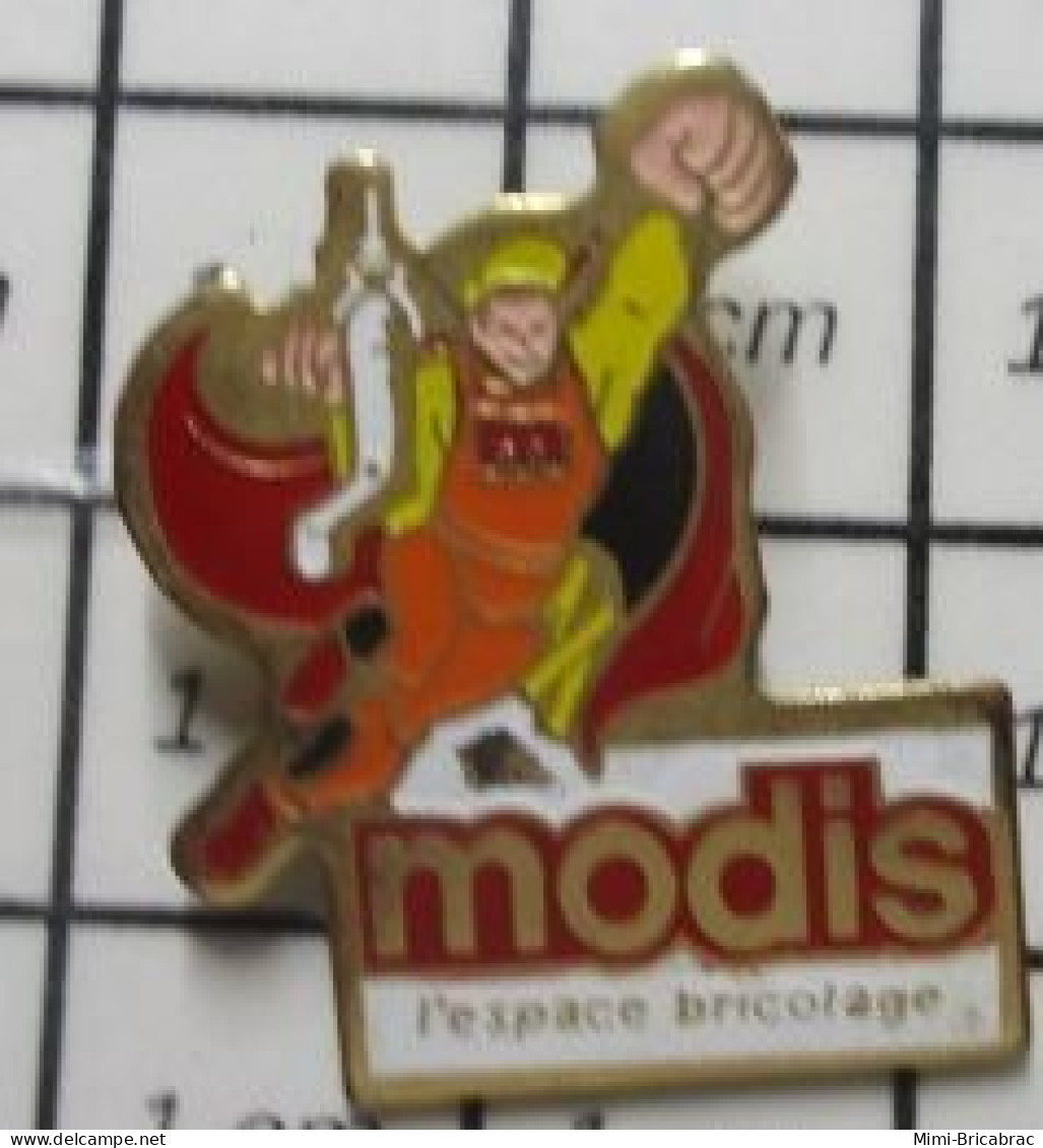 912e Pin's Pins / Beau Et Rare / MARQUES / MODIS L'ESPACE BRICOLAGE Super Heros En Salopette Orange - Administration