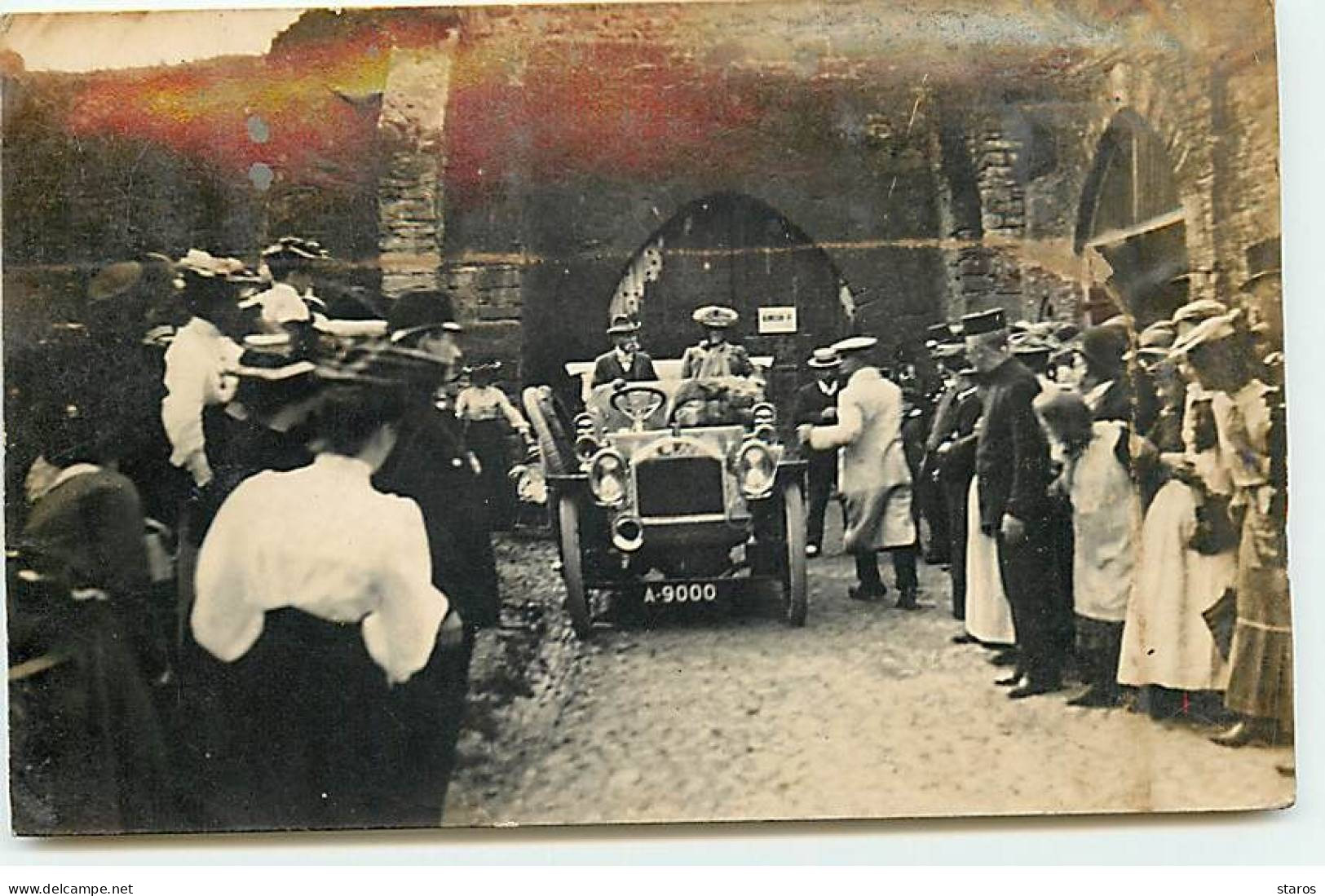 Carte Photo - Transport - Automobile - Couple Dans Une Voiture Passant Dans Une Rue Avec Des Spectateurs - PKW