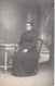 PHOTOGRAPHIE - VIEILLE FEMME BRUNE - ASSISE - CHAISE - TABLE - LONGUE ROBE NOIRE - CARTE POSTALE ANCIENNE - Photographie