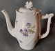 Cafetière En Porcelaine, Blanche Motif Floral Violet. Un Casse Sur Le Bec Verseur. - Sonstige & Ohne Zuordnung