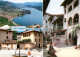 13246532 Caslano Panorama Luganersee Ortsmotiv Mit Brunnen Gasse Caslano - Altri & Non Classificati