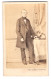Fotografie L. Haase & Co., Berlin, Grosse Friedrichstr. 178, älterer Herr Im Anzug Mit Fliege Stehend Am Tisch  - Anonyme Personen