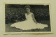 A Woman Sits On The Grass As Her White Dress Spreads - Anonymous Persons