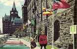 ROYAL CANADIAN MOUNTED POLICE CORPORAL AND VISITOR ADMIRE FLAGS OF MANY COUNTRIES ON PARLIAMENT HILL. - Ottawa