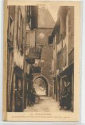 Aveyron - 12 - Mur De Barrez La Grande Rue Et La Tour De L'horloge Percée D'1 Porte Ogival Café Delmas Animée - Other & Unclassified
