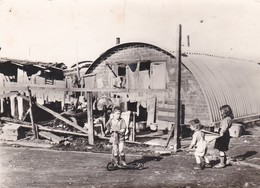 Cpsm 10x15 BIDONVILLE (ni Datée Ni Située Région Parisienne?) Enfants+ Trottinette Devant Baraques En Tôle Ondulée - Photos