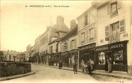 Delcampe - 91 DOURDAN LES COMMERCES RUE CHARTRES CHAUSSURES COCHET PAPETERIE IMPRIMERIE JOUETS ARMES BOULANGERIE HOTEL DE LYON - Dourdan