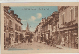 Auzances  23   La Rue De La Poste Tres Tres Animée -Coiffeur-Tabac-Journaux-Cycles-Café-Epicerie Et Voiture - Auzances