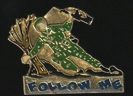 72917-Pin's.Follow Me Est Une Marque Qui Fabrique Des Vêtements Et Des Accessoires Type Camouflage - Militaria