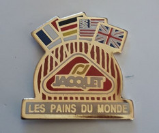 BD329 Pin's Boulanger Boulangerie Pain Les Pains Du Monde Jacquet Groupe Jacquet Brossard Achat Immédiat - Alimentation