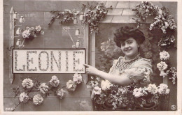 Femme Souriante Montre Du Doigt Le Prénom LEONIE - Carte Postale Ancienne - Frauen