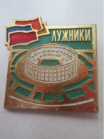 Petit Insigne Plastique Russe à épingle / AYXHNKN / Grand Stade Avec Drapeaux/ Vers 1980     INS114 - Autres & Non Classés