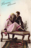 COUPLES - Un Couple Assis Sur Une Banquette - Femme Tient Des Fleurs - Gui - Tapis - Carte Postale Ancienne - Koppels